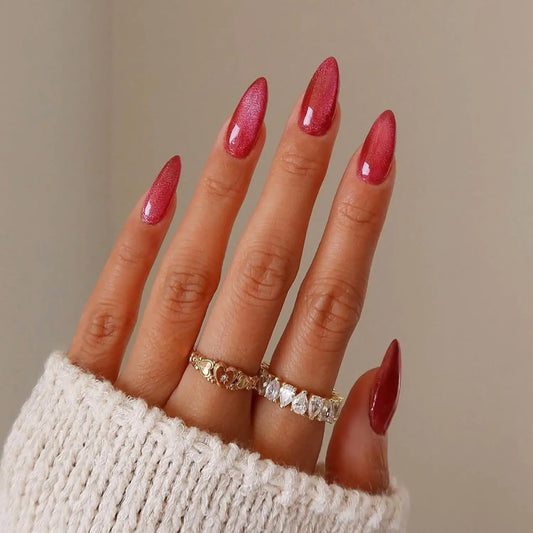 Close-up of a hand with red nail polish and multiple rings on a neutral background