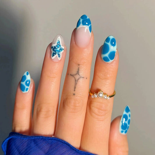 Hand with blue and white patterned nails against a neutral background