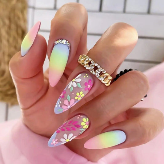 Hand with colorful gradient and floral nail designs, wearing a gold ring.