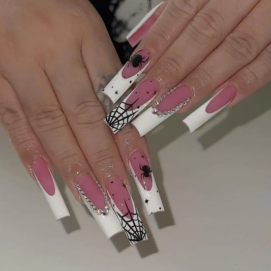 Nails with pink and white design featuring spiders and web patterns on a neutral background.