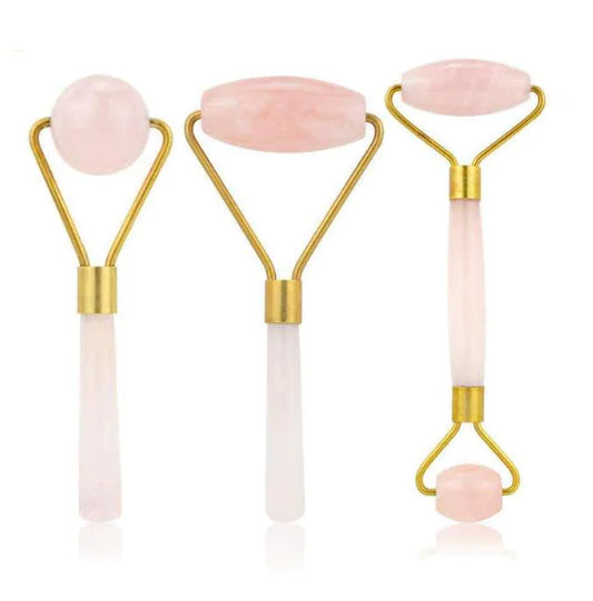 Three facial roller tools with pink stones on a white background