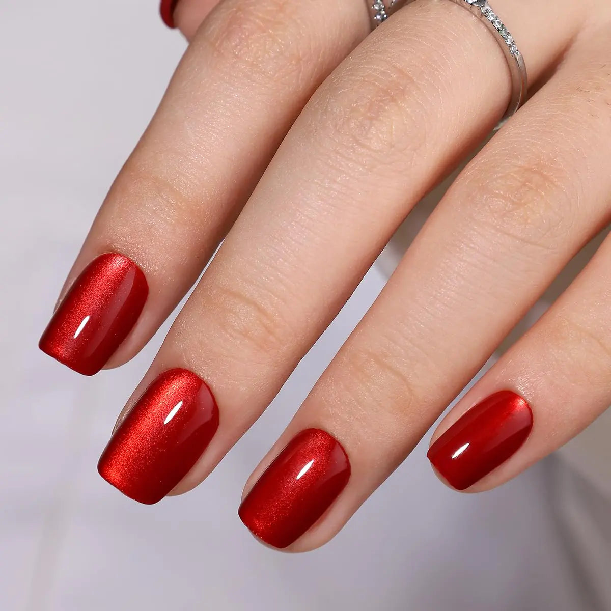 Hand with red nail polish on a neutral background