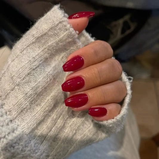 Hand with red nail polish wearing a light gray textured sleeve.